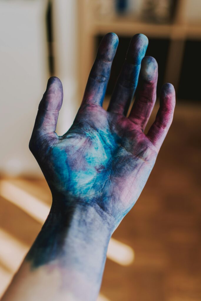 Blau und violett bemalte Hand beim intuitiven Ausdrucksmalen